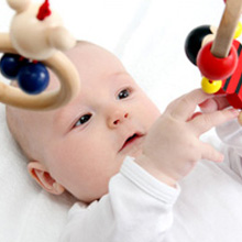 Baby greift nach dem Montessori Puzzleball auf der Spielmatte